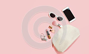 Flat lay female accessories cosmetics sunglasses mobile phone headphones flash drive makeup on pastel pink background. Valentine`s