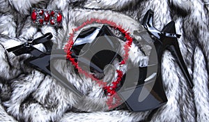 Flat lay female black high-heeled shoes and red accessories collage on wolf fur background. Female sandals with high heels