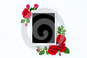 Flat lay floral frame with tablet, red and beige rose flower buds on white background.