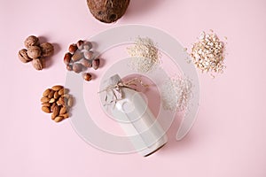 Flat lay food composition with a plant based milk and wholesome nuts, cereals and seeds on pink background. Copy space