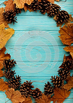 Flat lay frame of autumn leaves, cones and nuts on a wooden back