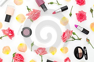 Flat lay frame composition with pink roses flowers and feminine cosmetics on white background. Top view