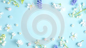 Flat lay frame from spring flowers on a light blue background. View from above, copy space. Beautiful floral frame