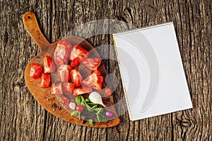 Flat-lay of fresh colorful ripe Fall or Summer heirloom tomatoes variety over rustic tray background with blank paper