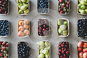 Flat-lay of fresh fruits and berries over grey concrete background