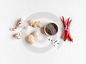 Flat lay of fresh garlic, black pepper in bowl, red chili and ginger on a light background. top view. Copy space