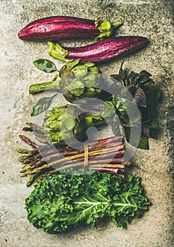 Flat-lay of fresh green and purple vegetables, vertical composition