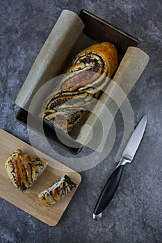 flat lay with a freshly baked delicious wicker poppy seeds bun and a knife