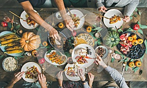 Flat-lay of friends feasting at Thanksgiving Day table with turkey