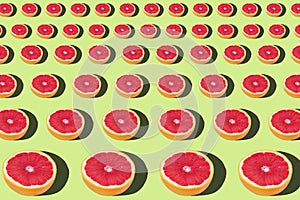 Flat lay fruit pattern of fresh grapefruit slices on green background