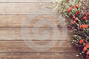 Flat lay of garden spring white and red tiny flowers on wooden plank table background with copy space, retro color style.