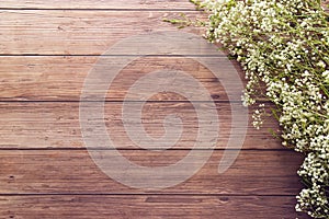 Flat lay of garden spring white tiny flowers on wooden plank table background with copy space, retro color style.