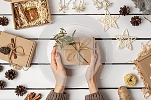 Flat lay of gift craft boxes, pine cones, cinnamon sticks, dried flowers and Christmas decorations on a wooden light background.