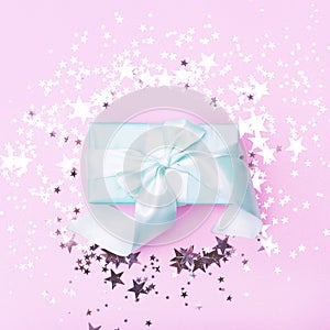 Flat lay with a gift with a large bow of mint color on a pink background