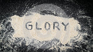 Flat lay of GLORY text written on white sand