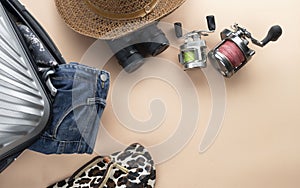 Flat lay grey suitcase with binoculars, hat, jeans, spinning for fishing and sandles on pastel background. travel concept - Image