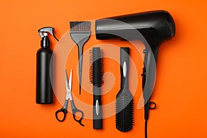 Flat lay hairdresser accessories on orange background, top view