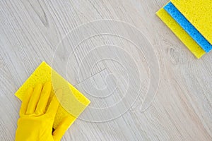 Flat lay. Hand in yellow rubber protective glove cleaning parquet floor with rag at home, copy space.