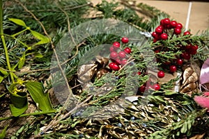 Flat lay of handcrafting supplies for red and green Christmas decorations with green fir branches and artificial red berries.