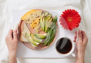 Flat lay of healthy bed breakfast with avocado, cheese and bread