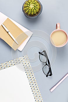 Flat lay home office desk. Female workspace with note book, eyeglasses, tea mug, diary, plant. Copy space