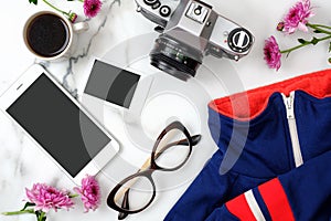 Flat lay home office desk. Female workspace with stylish clothes, glasses, photo camera, phone, coffee cup, instant image, flowers