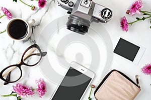 Flat lay home office desk. Feminine workspace with mobile phone, glasses, vintage photo camera, coffee cup, instant image and