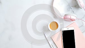 Flat lay home office desk. Women workspace with headphones, smartphone with empty screen mockup, pink paper notebook, pen, coffee