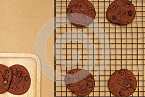 Flat lay of homemade sweets, Chocolate cookie on rack and stack in wooden tray over wood background