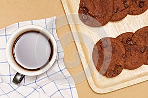 Flat lay of homemade sweets, Chocolate cookies are stack on plate and coffee over wood background