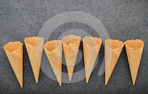 Flat lay ice cream cones collection on dark stone background . Blank crispy ice cream cone with copy space.