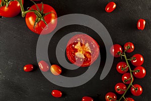 A flat lay image featuring a medley of tomatoes on black wooden background.