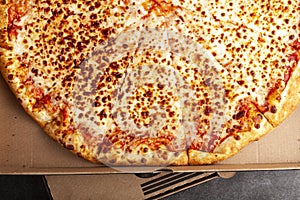 Flat lay image of a fresh baked store bought sliced four cheese pizza in cardboard pizza box.