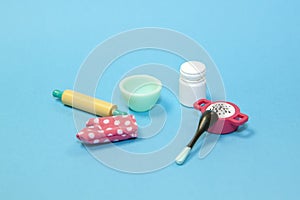 flat lay image of plastic toy tableware with kitchen oven mitt glove on pastel blue background