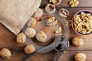 walnuts in shell with nut cracker on wooden background