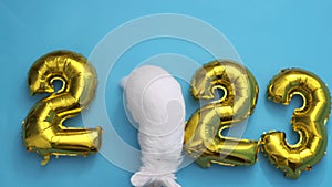 flat lay inflatable golden balloons in the form of numbers 2023 on blue background. Year of the rabbit. White rabbit