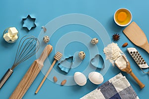 Flat lay ingredients for baking and kitchen utensils on a blue background. Top view, place for your text