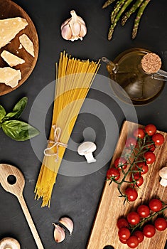 Flat lay of Ingredients for cooking italian pasta. Spaghetti, tomatoes, oil, garlic, parmezan. Top view of traditional italian cus