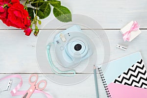 Flat lay Instant film camera and feminine accessories on pastel blue wooden background. Top virw frame set of beuty blogger items
