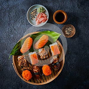 The flat lay of the Japanese food assortment - sushi, nigiri, tempura, maki, sashimi on dark background with copy space.