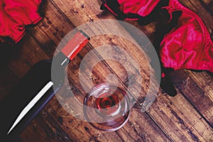 Flat lay of a ladies red bra and knickers with a bottle of red wine and wine glass