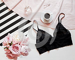 Flat lay. Top view black lace lingerie. Beauty blog concept. Bouquet of roses and pions, coffee on white bed background