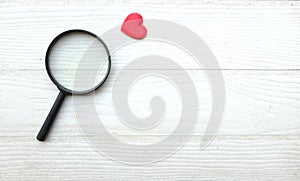 flat lay a magnifying glass and decorative red hearts isolated on a white wooden background