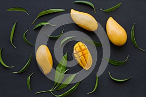 Flat lay of Mango tropical fruit with green leaf on black background