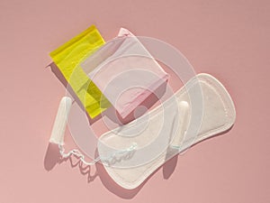 Flat lay menstrual tampons and pads on a pink background with hrad light. Menstruation cycle concept