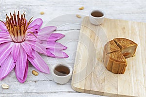 Flat lay of Mid Autumn festival Moon cake on old white table with pink water lily.