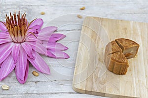 Flat lay of Mid Autumn festival Moon cake on old white table with pink water lily.