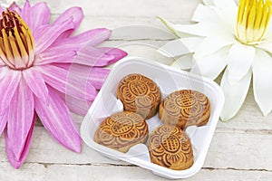 Flat lay of Mid Autumn festival Moon cake on old white table with pink water lily