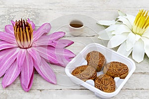 Flat lay of Mid Autumn festival Moon cake on old white table with pink water lily