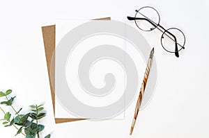 Flat lay Mockup blank Card with a calligraphy pen, glasses, and flower on a white table. Copy space